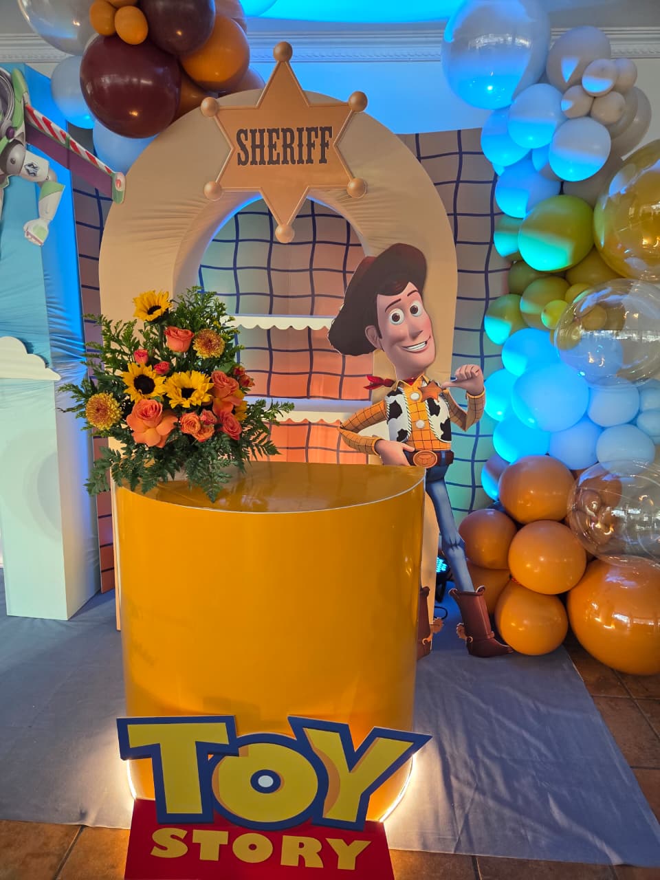 Barra amarilla de Toy Story con letrero luminoso y arreglo de girasoles