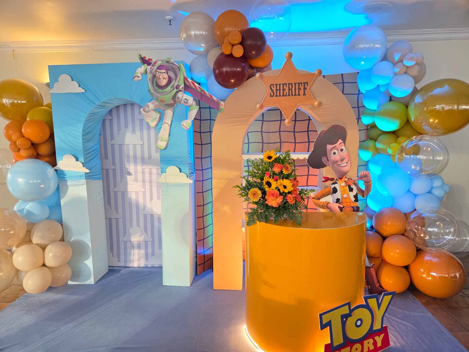 Escenografía completa de Toy Story con arcos de Buzz Lightyear y Woody, guirnaldas de globos y barra amarilla